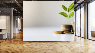 A close-up of a green plant growing from a pile of coins with a bright background, illustrating the growth of savings and investments Wall mural