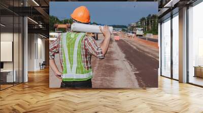 Architect holding rolled up blueprints at construction site Wall mural