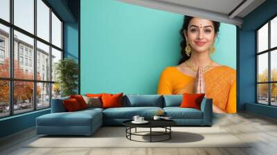 Beautiful indian woman doing namaste gesture or giving praying pose Wall mural