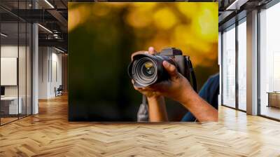 Closeup of a black camera holding by Photographer's hand with sunset background Wall mural