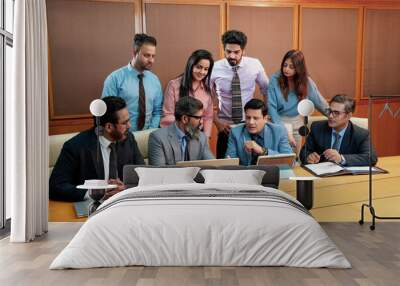 Indian businesspeople group working together and looking in laptop at meeting hall. Wall mural