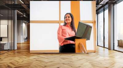 Indian corporate woman standing on office stair and using laptop. Wall mural