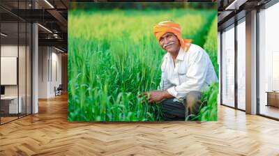 Indian farmer holding crop plant in his Wheat field Wall mural