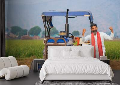 Indian farmer standing near tractor and giving expression at agriculture field. Wall mural