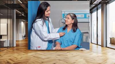 Indian female doctor using a stethoscope for check up on bed at hospital. Wall mural