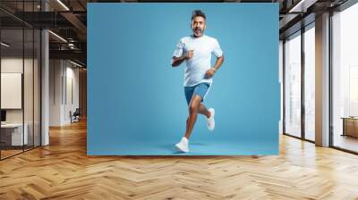 indian man in sport wear and running on blue background. Wall mural