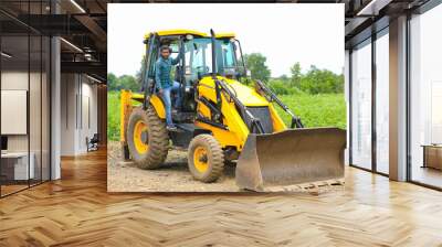 Indian man working with heavy equipment vehicle at construction site. Wall mural