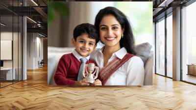 Indian school boy holding trophy sitting with mother Wall mural