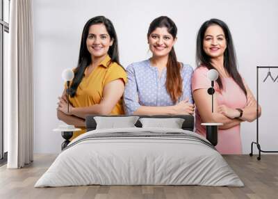 Three indian women giving expression together on white background. Wall mural