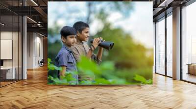 Tow little Indian boy enjoys in nature with binoculars Wall mural