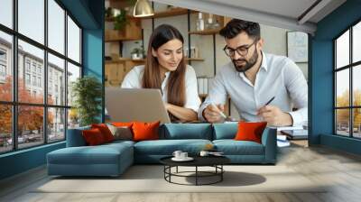 Two busy colleagues working together talking using laptop in office. Wall mural