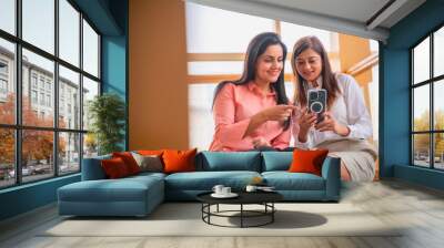 Two Indian corporate woman using smartphone at office. Wall mural