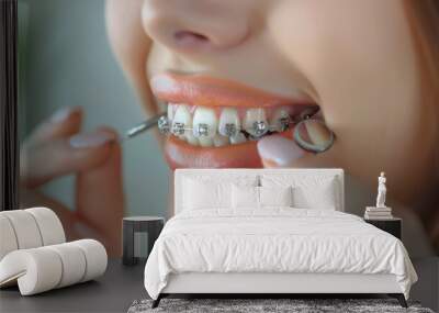 Woman with dental braces cleaning teeth Wall mural