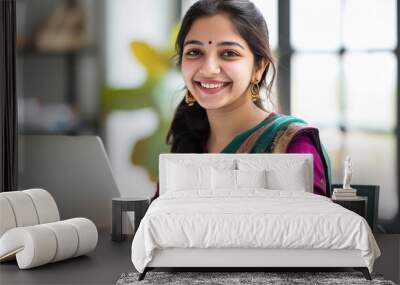 young beautiful indian girl looking front side smiling while working on laptop Wall mural