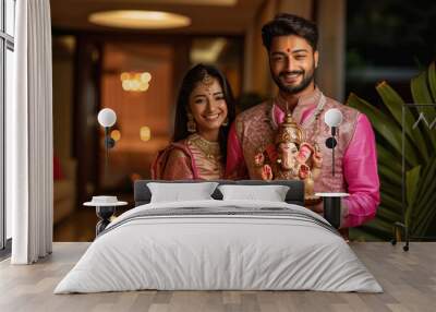 Young indian couple holding lord ganesha sculpture. celebrating lord ganesha festival. Wall mural