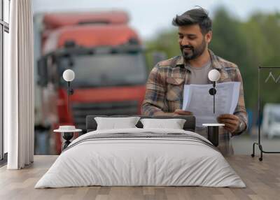 Young indian male truck driver or owner checking paper Wall mural