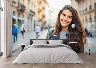 Smiling woman using a smartphone in a city street. Wall mural