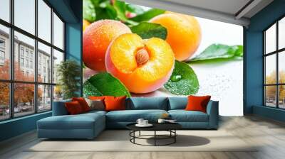 A close-up shot of fresh apricots with green leaves on a white background. The apricots are juicy and plump, and the leaves are vibrant green. Water droplets adorn the surface, representing freshness  Wall mural