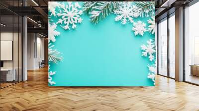 A festive winter scene with white snowflakes and frosted pine branches arranged on a turquoise background, creating a whimsical and celebratory backdrop for holiday designs. Wall mural