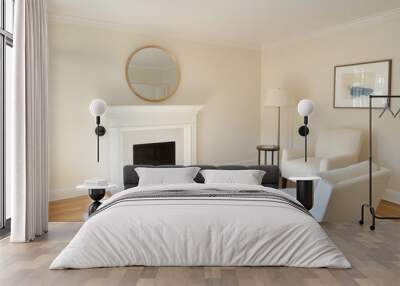 A peaceful living room with a fireplace, a round mirror above the mantel, and two white armchairs.  The room is bathed in natural light, creating a sense of calm and tranquility. The artwork on the wa Wall mural