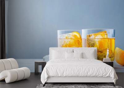 Two glasses filled with orange cocktails, garnished with orange slices, and served with ice cubes on a white marble table. The refreshing drinks symbolize relaxation, celebration, and summertime enjoy Wall mural