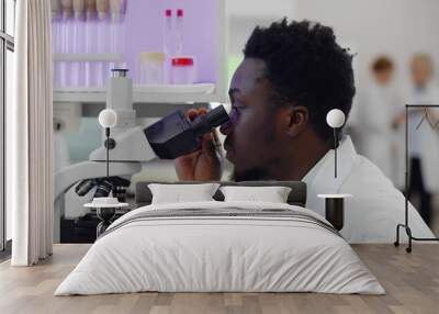 African-american man making medical research using microscope working in lab Wall mural