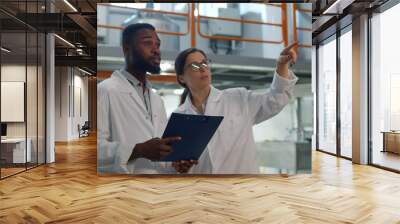 African and caucasian inspectors in white coat controlling industrial manufacture Wall mural