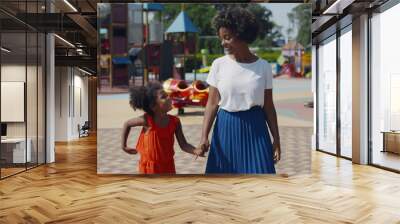 Afro mother and daughter holding hands walk at playground Wall mural