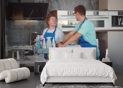 Janitors in uniform pushing cart with cleaning equipment in modern kitchen interior Wall mural