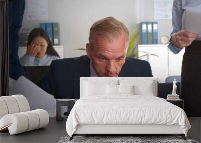 Mature businessman in office working under pressure from colleagues Wall mural