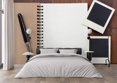 Blank notebook with pen and photo frames on wooden background. Wall mural