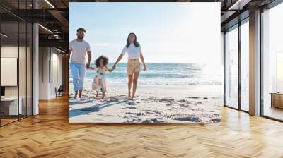 A walk in the sunshine. Full length shot of an affectionate young family of three taking a walk on the beach. Wall mural