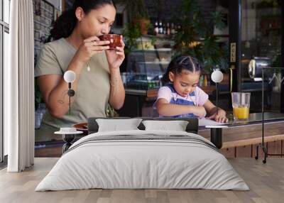 Coffee shop, black family and art with a mother and daughter coloring in a book at a cafe together. Color, caffeine and crayons with a woman and happy female child bonding in a restaurant Wall mural