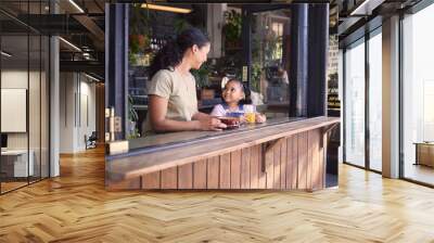 Coffee shop, black family and children with a mother and daughter enjoying a beverage in a cafe together. Juice, caffeine and kids with a woman and happy female child bonding in a restaurant Wall mural