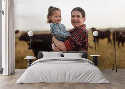 Family, mother and baby on a farm with cows in the background eating grass, sustainability and agriculture. Happy organic dairy farmer mom with her girl and cattle herd outside in sustainable nature Wall mural