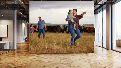 Happy family bonding on a cattle farm, walking and looking at animals, relaxing outdoors together. Young parents showing child girls how to care for livestock and having fun on exploring nature walk Wall mural