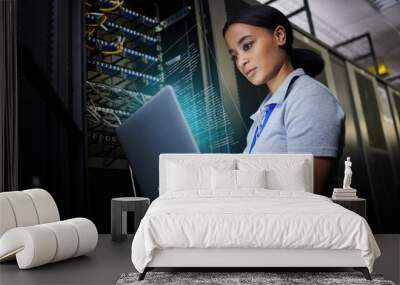 Laptop, network and data center with a black woman it support engineer working in a dark server room. Computer, cybersecurity and analytics with a female programmer problem solving or troubleshooting Wall mural