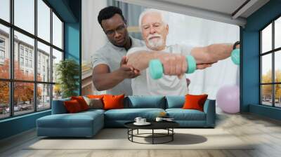 Physiotherapy, dumbbell arm exercise or old man for rehabilitation, recovery and black man support on injury healing. Helping, aid service or African physiotherapist advice elderly patient on workout Wall mural