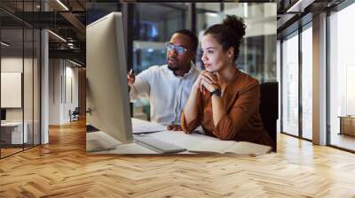 Business training, night planning and employees talking about corporate proposal on internet in dark office at night. African workers working on partnership on the web with computer during overtime Wall mural