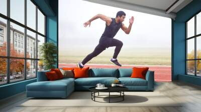 Gaining some serious speed. Full length shot of a handsome young male athlete running on an outdoor track. Wall mural