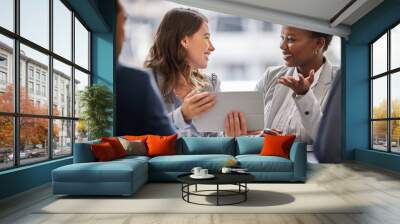 I understand exactly what you mean. Shot of two young businesswomen sitting together in the office and having a discussion while using a digital tablet. Wall mural