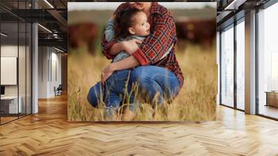 Love, family and care with a mother and daughter hugging in a field outside on a farm. Cattle farmer and little girl in the farming, agricultural and dairy industry on a meadow or pasture outdoors Wall mural