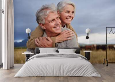 Mature couple embracing and looking happy while bonding outdoors at a farm, carefree and loving. Senior husband and wife having peaceful day in nature, enjoying retirement and relationship Wall mural