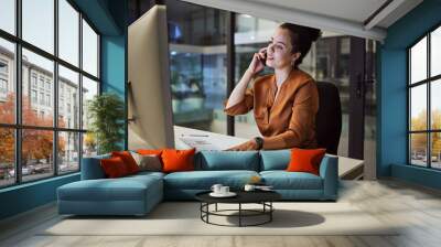 Phone call, communication and networking with a business woman working on a computer in her office late at night. Research, report and deadline with a female employee at her work desk for overtime Wall mural