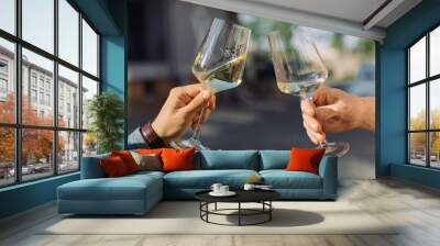 Men making celebratory toast with glasses of white wine at summer party. Golden light, relax concept. Wall mural