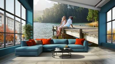 Young couple, lake and jetty with laughing, happiness and bonding with love in nature for holiday. Man, woman and comic joke on bridge by water to relax with conversation, care and vacation in summer Wall mural