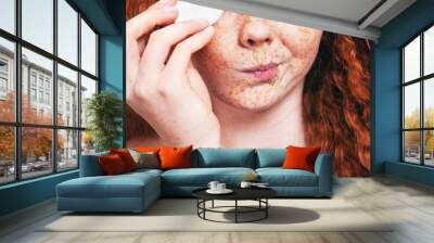 make up removal concept, freckled girl with cotton pad Wall mural