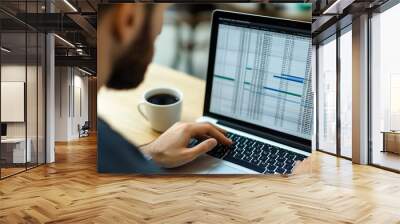 A data analyst reviewing a large spreadsheet filled with rows and columns of data, with a cup of coffee next to the laptop, organized, focused Wall mural