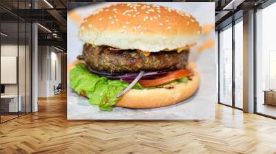 Delicious juicy burger on white wrapping paper background. Cutlet, cheese and vegetables inside fresh sesame bun. delicious street food, fast food, beef burger, close up Wall mural