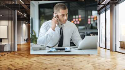 Asian Businessman sitting in office using a cellphone and laptop. Wall mural